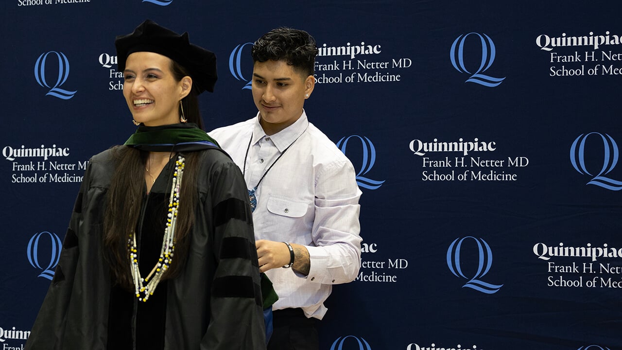 Graduate smiles as they receive their hood