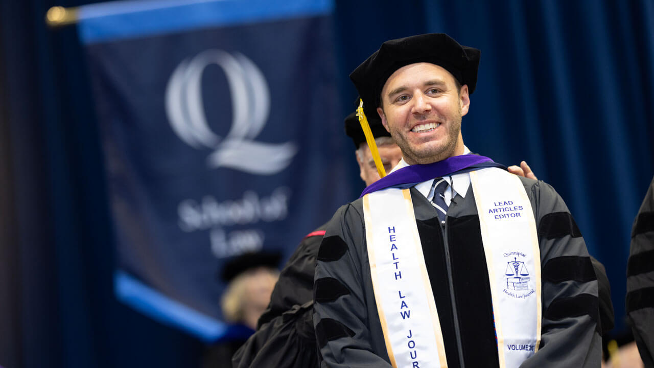 Student wearing cap and gown with his hood