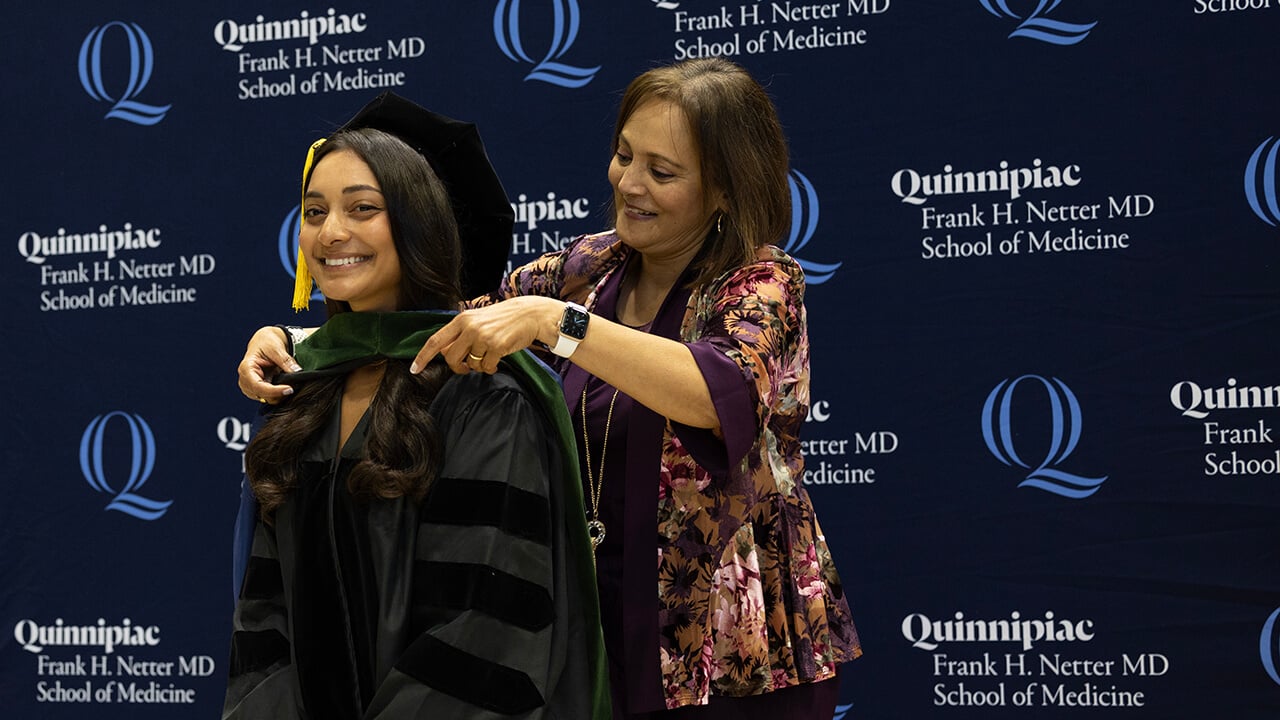 Smiling graduate receives hood