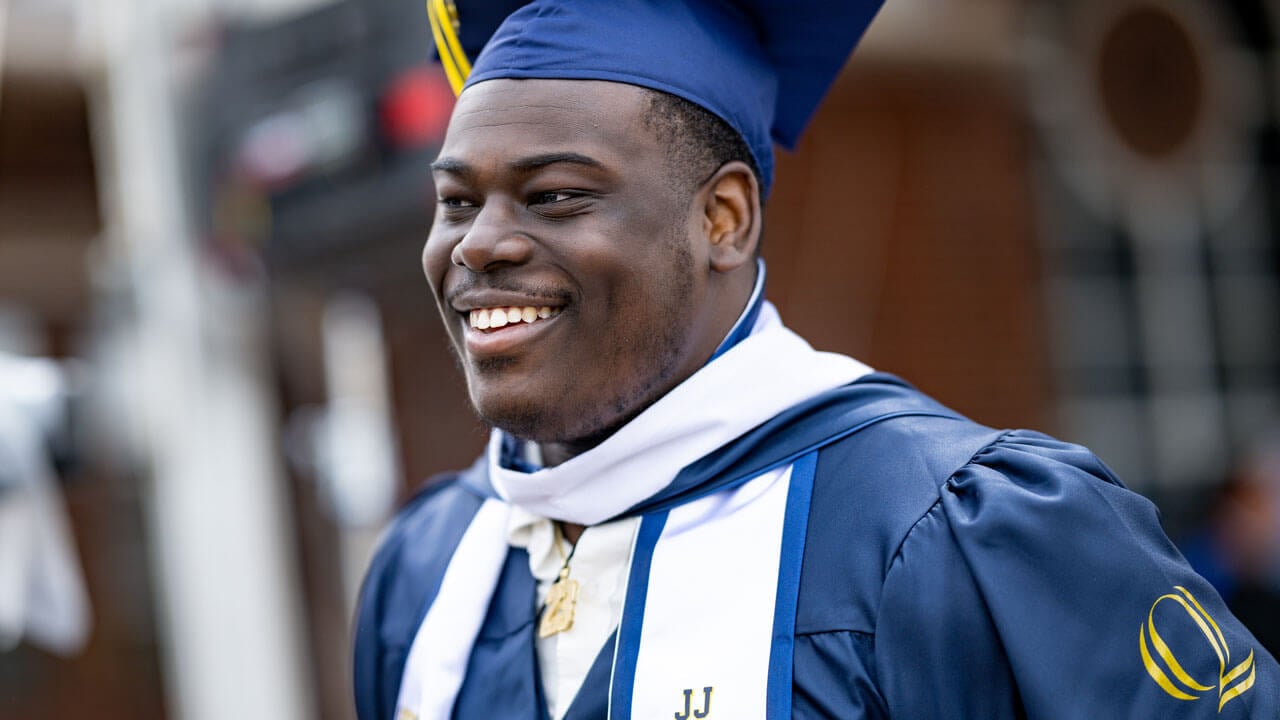 SOC graduate smiling with his cap and tassel on the right hand side