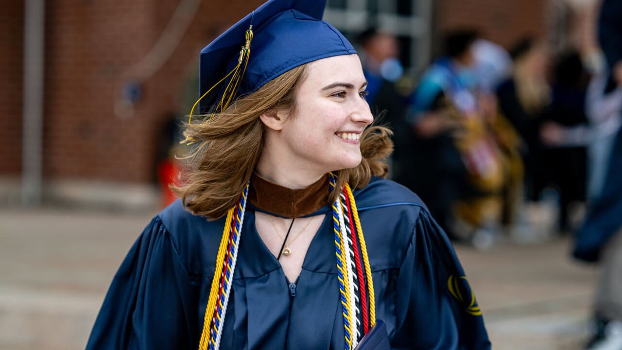 Graduate smiles with her head turned looking at the families