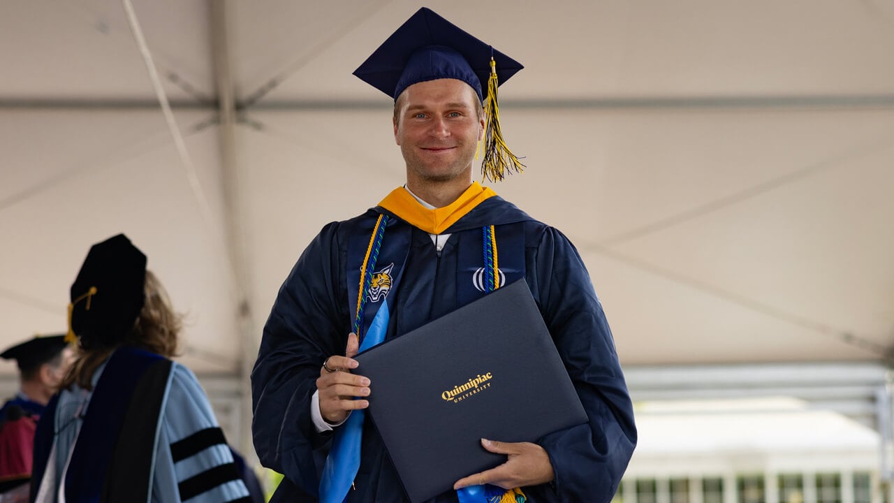 Student walks across stage holding degree