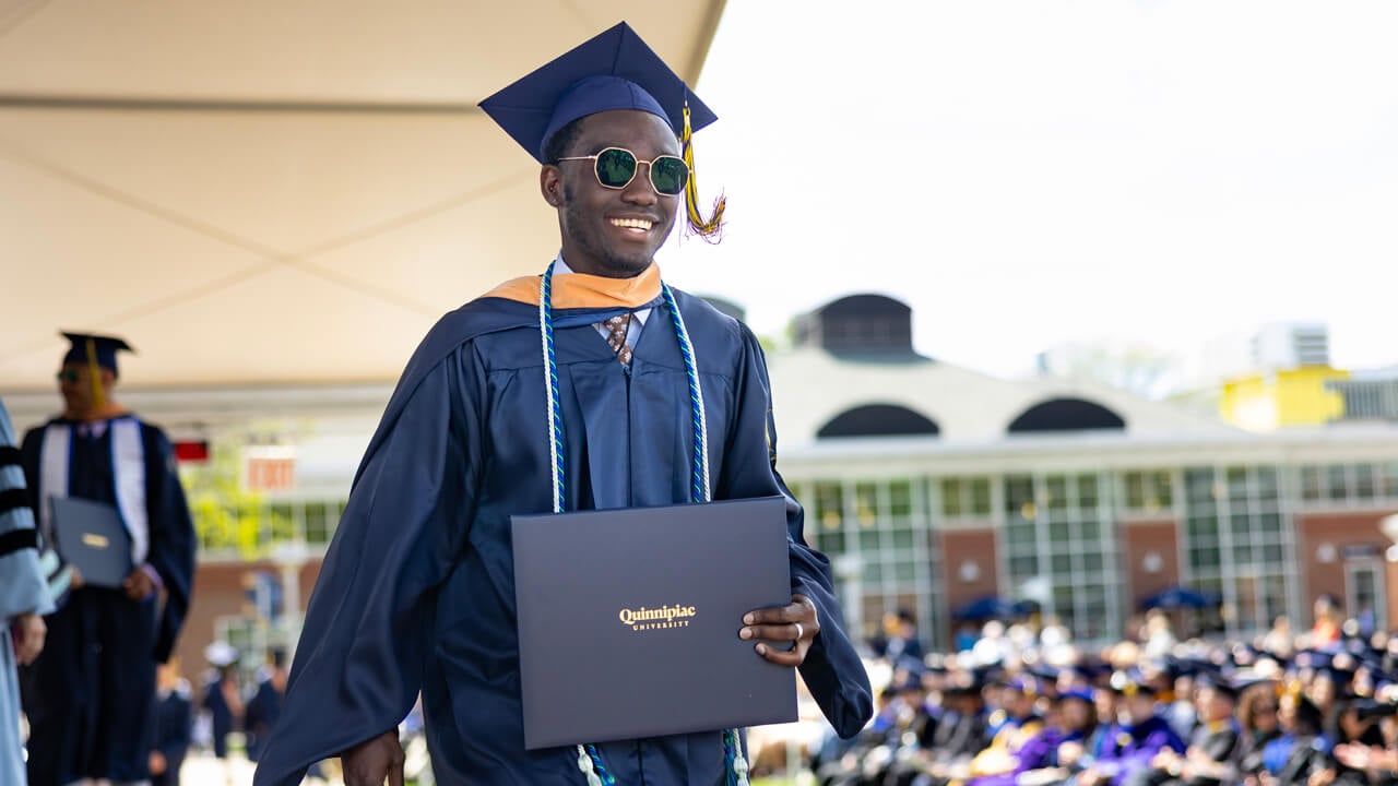 Student walks across the stage holding degree