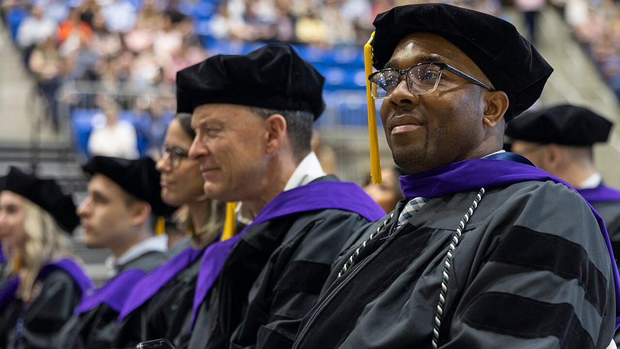 Seated graduates listen to the speakers on stage