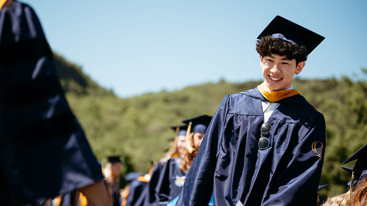 A graduate smiling as they process in