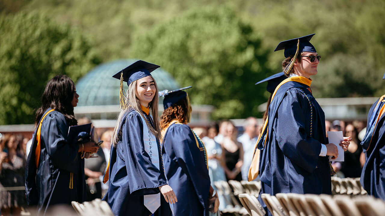 A grad smiling with Lender School of Business behind them