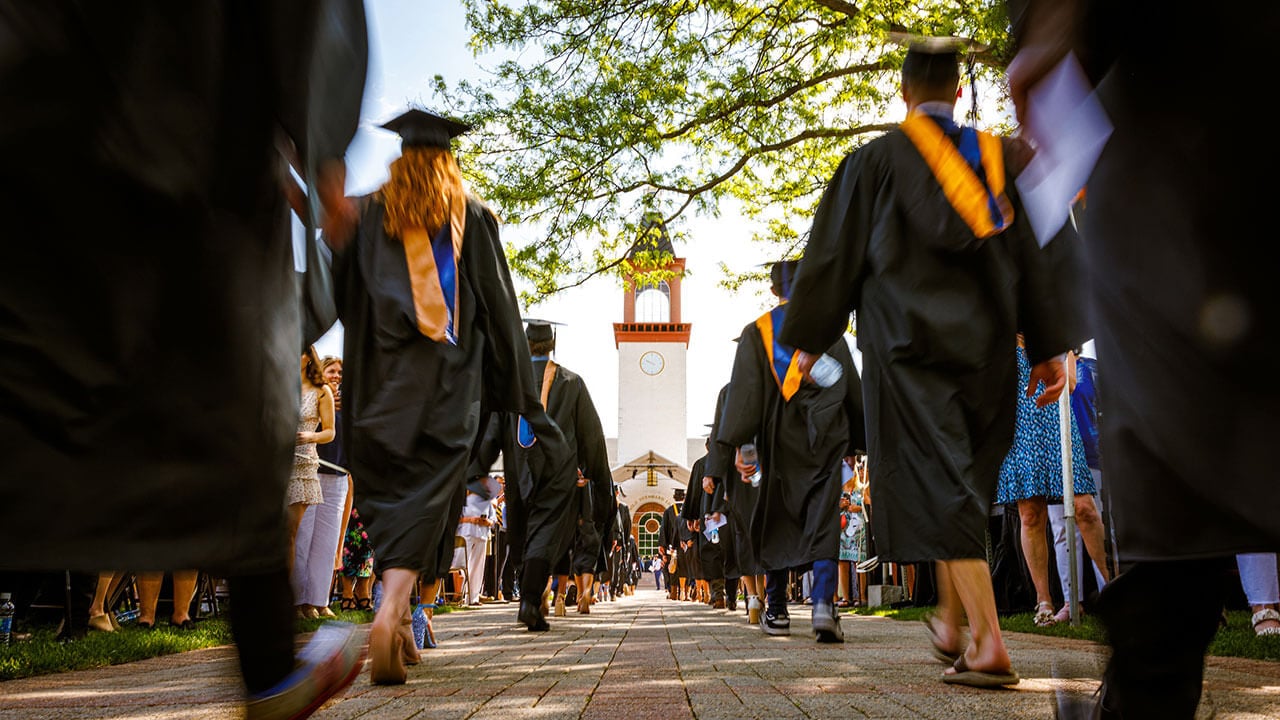 View of the clocktower while graduates walk across the Quad