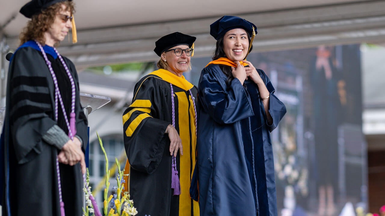 Graduates and professors smiling towards the audience