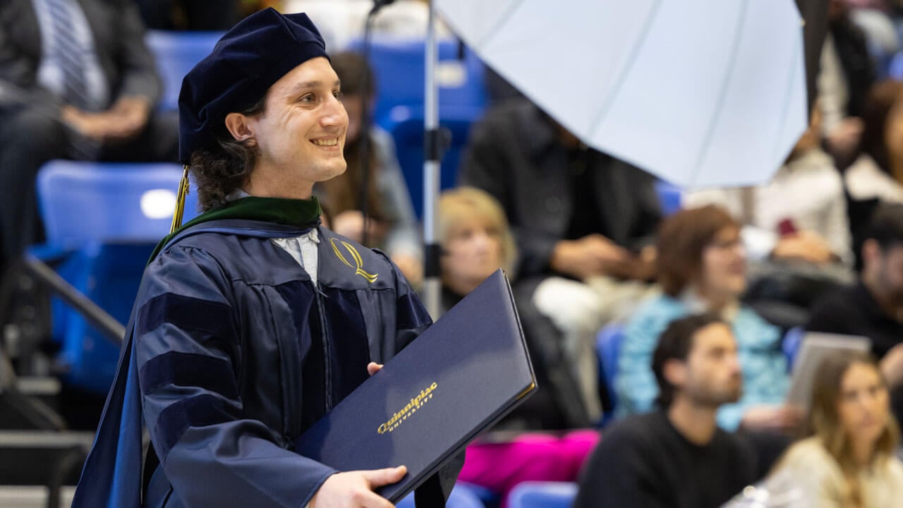 A proud class of 2024 law student grins after receiving their diploma.