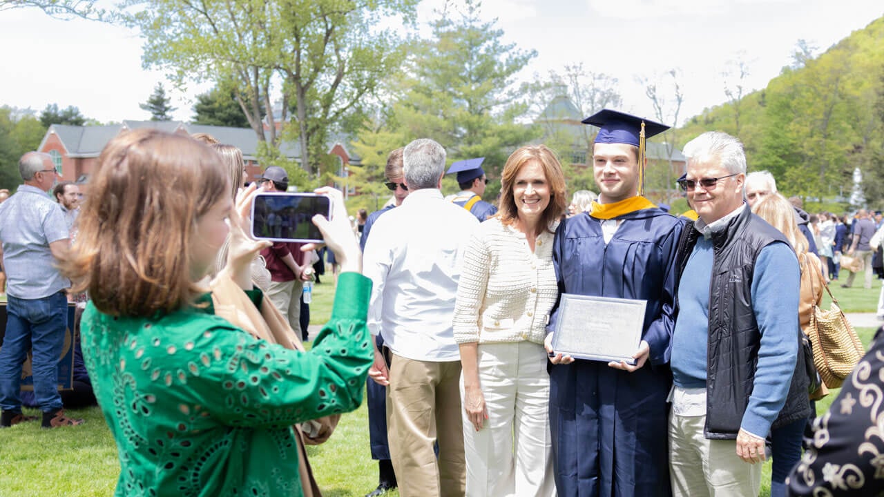 Graduate poses with his family for a photo on the quad