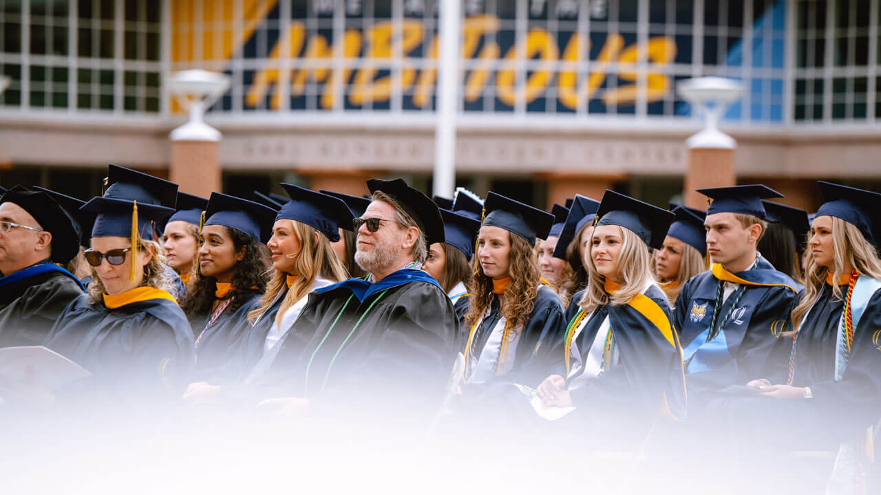 A group of health science graduates sit patiently and listen closely to a speech before receiving their diplomas.