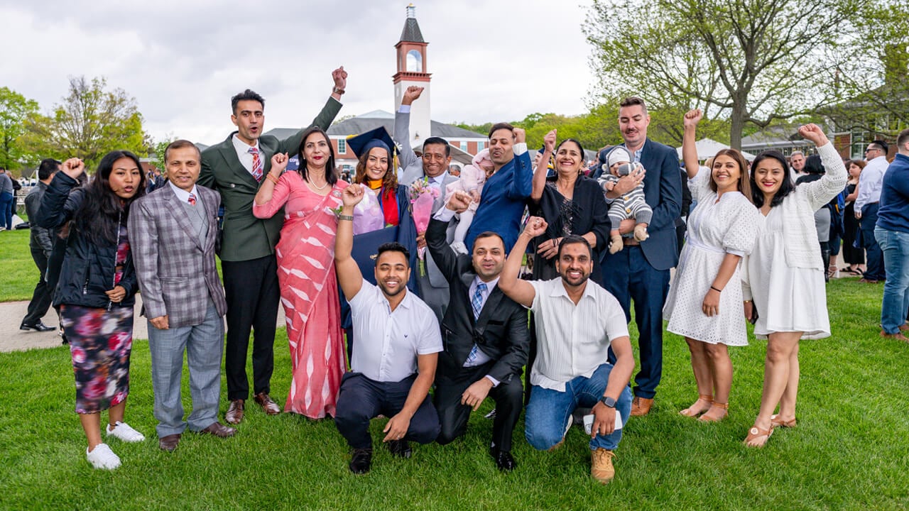 A large multi-generational family cheers and poses for a photo in front of the clocktower