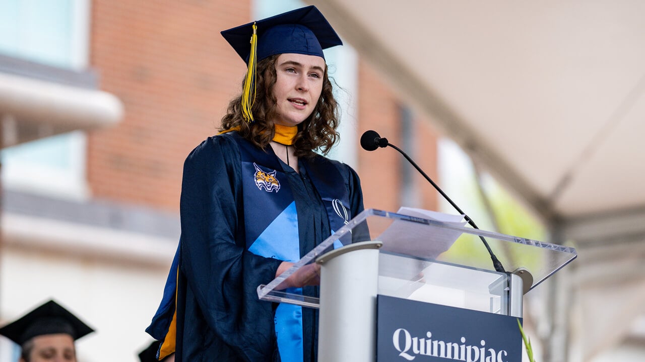 Kathryn Reilly stands at a podium with a microphone as she speaks