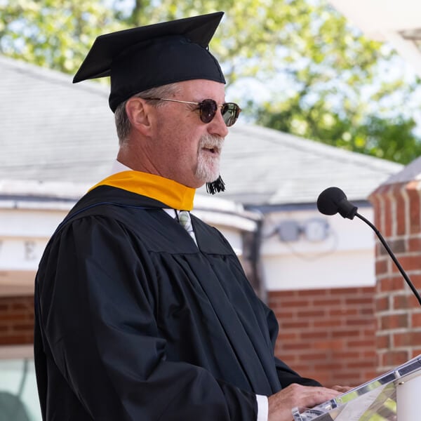 Paul Benjamin rests his hand on the podium and speaks into a microphone