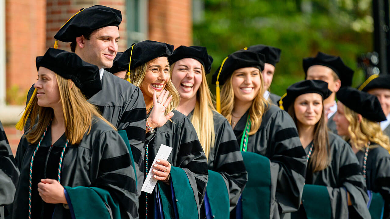 graduates smile and wave from their line up