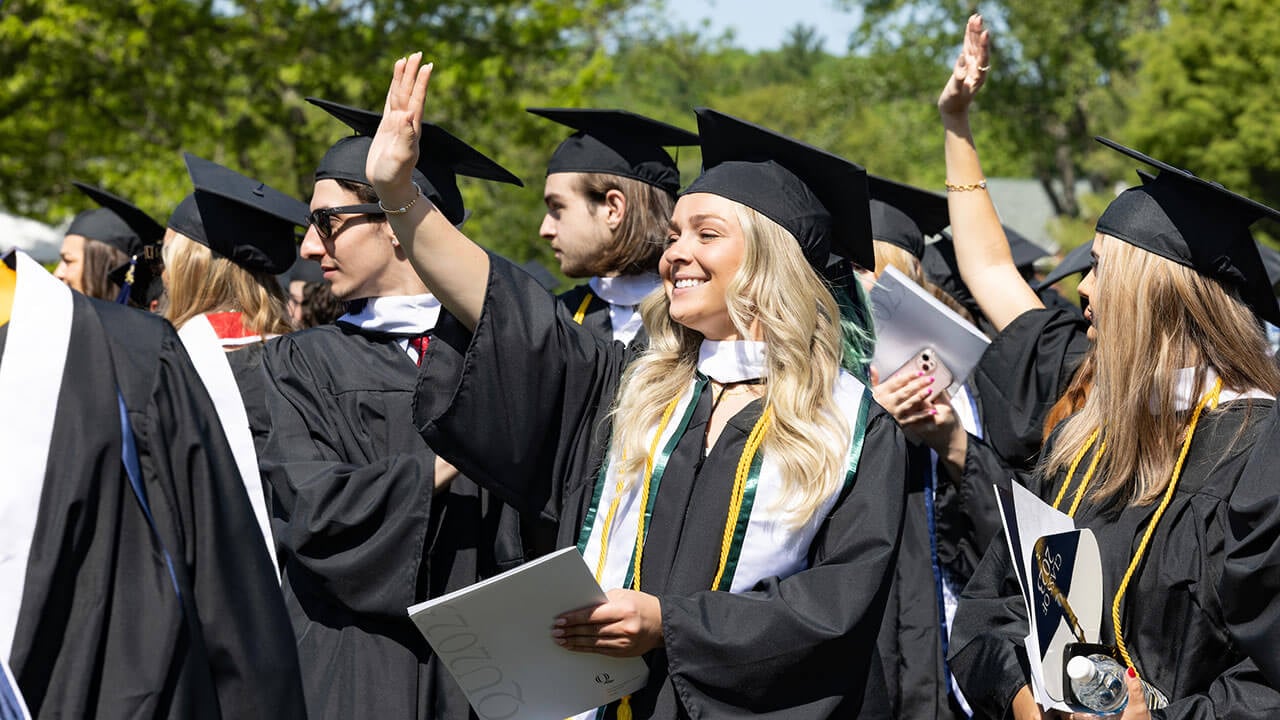 group of graduates wave to their friends and families off camera