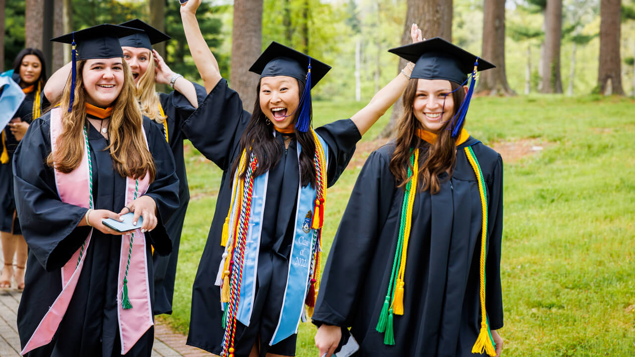 Three graduates smile and cheer for a photo