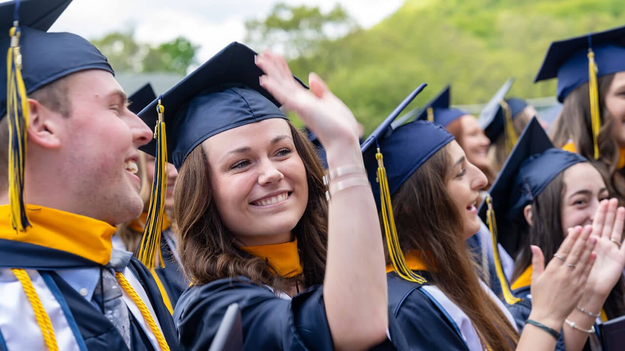 graduate smiles and waves