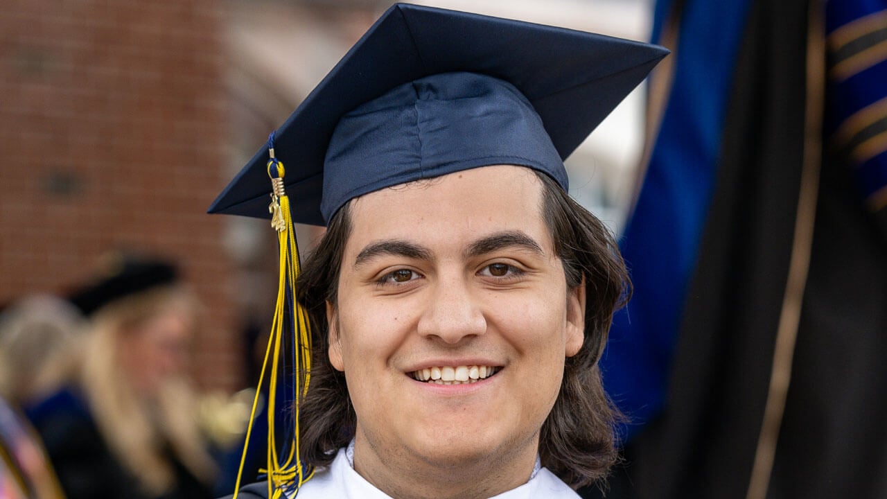 Quinnipiac Graduate smiles at the camera