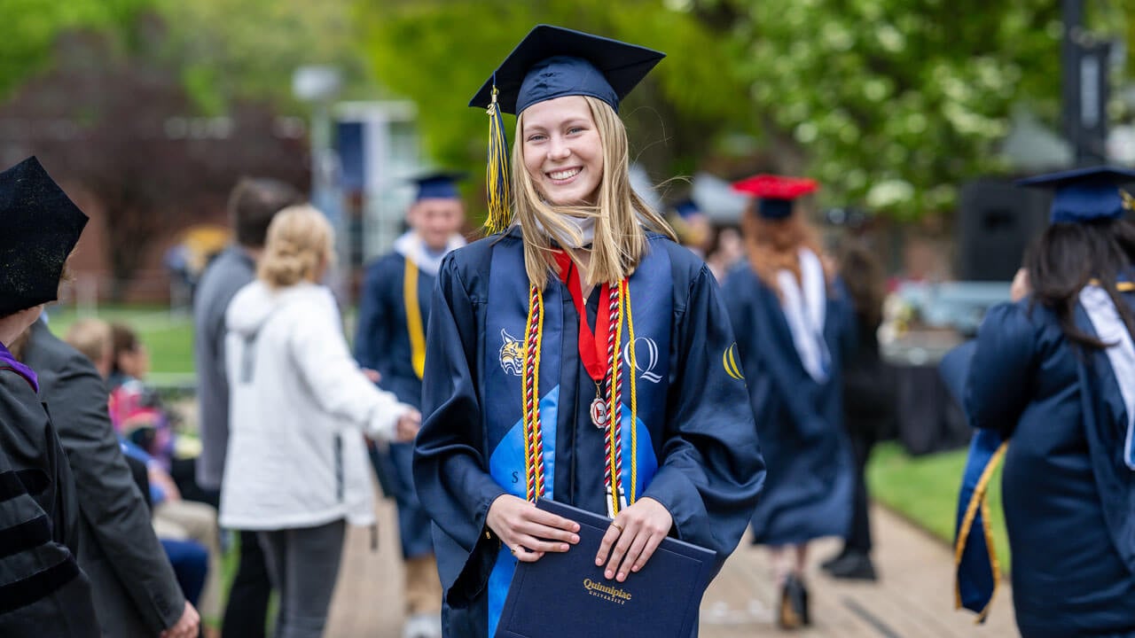 Graduate smiles and poses with her degree