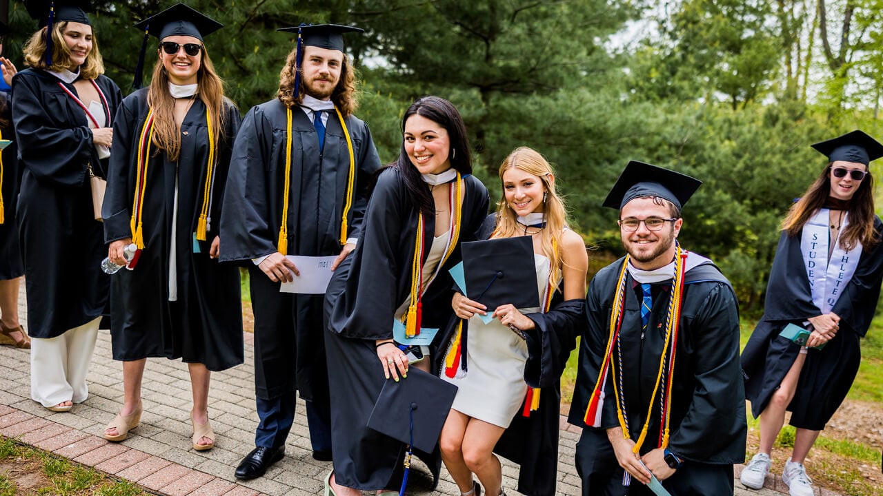 Graduates smile as they walk to Commencement