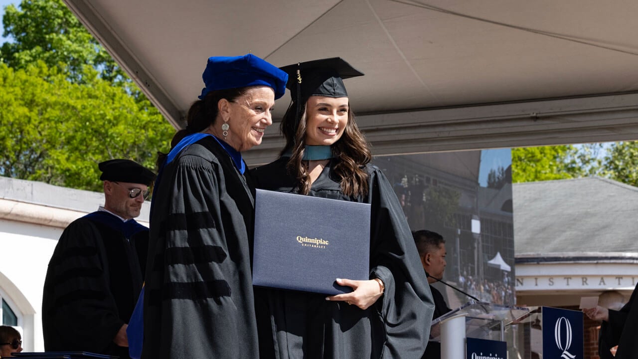 Graduate takes photo with the dean both smiling happily