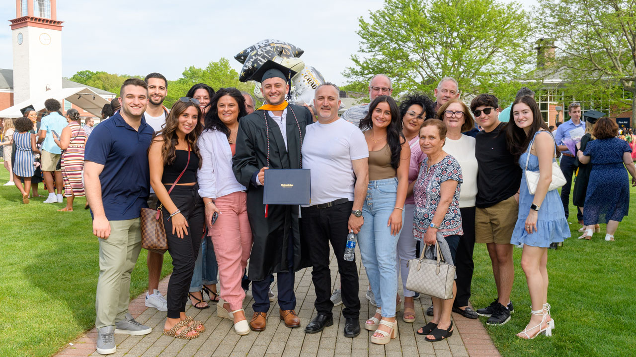 Whole group photo with recent graduate all smiling happily for his success