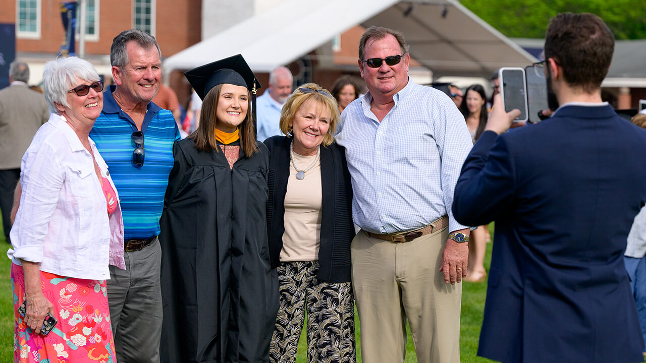 Family and friends surround graduate for a photo in front of Arnold Bernhard library