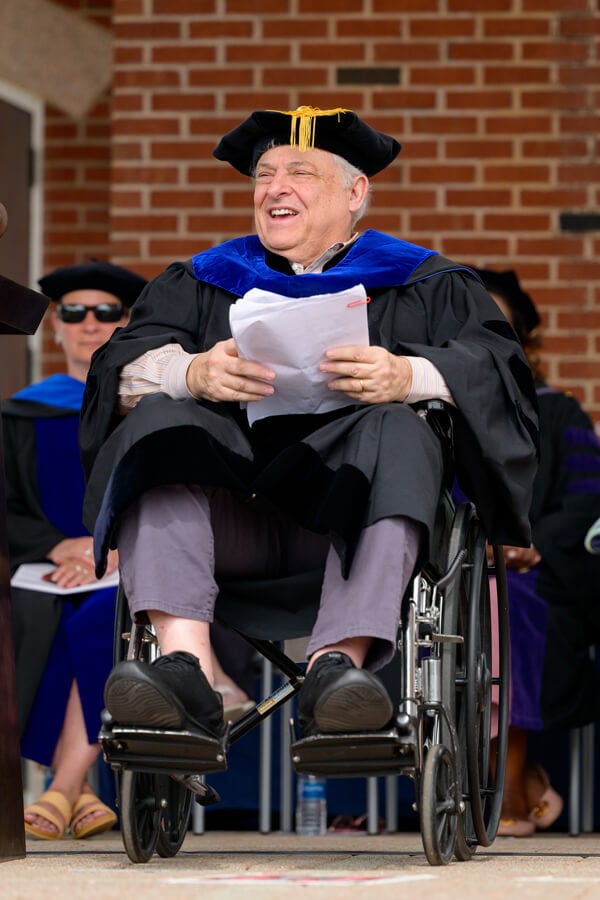 Arthur Caplan holds papers and delivers his remarks from the library steps