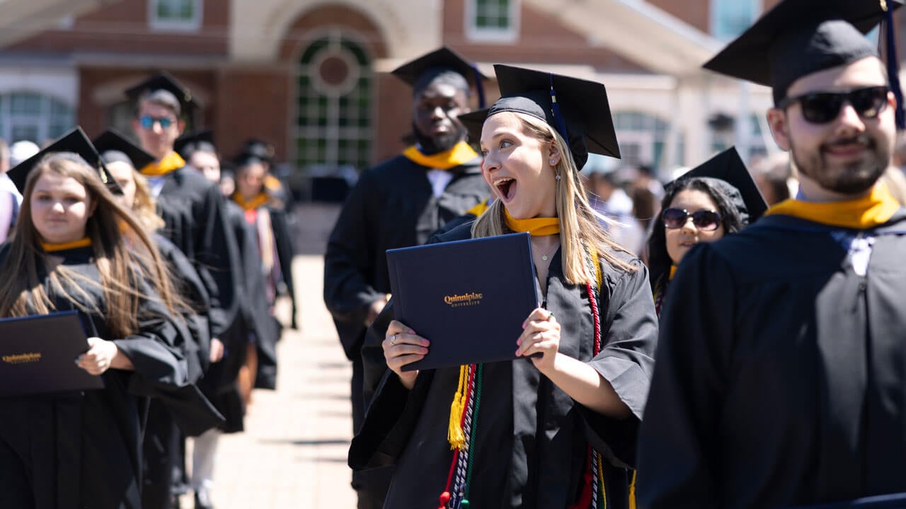 Graduate astonished holding diploma and smiles