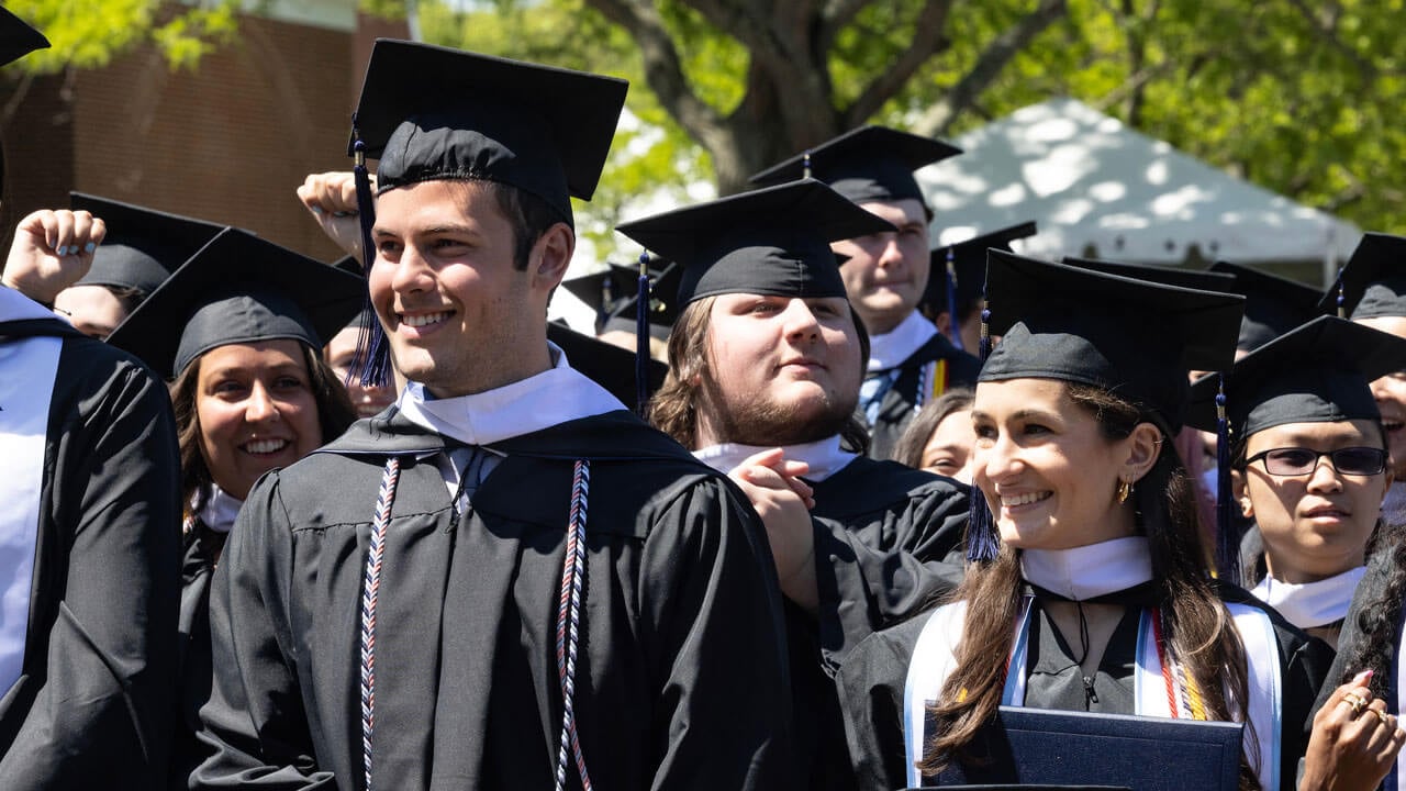 Graduates cheerfully standing, clapping and smiling