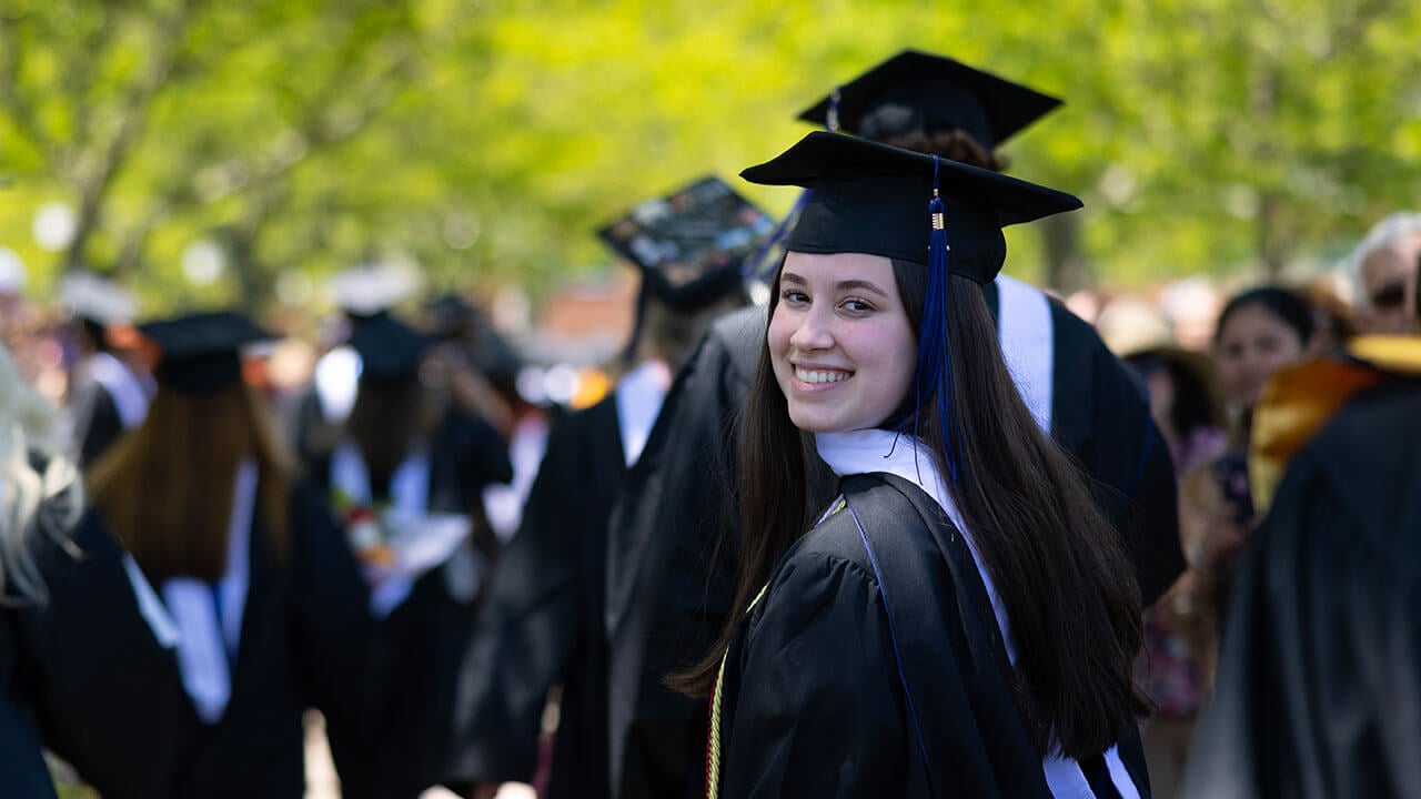 graduate looks over her shoulder and smiles