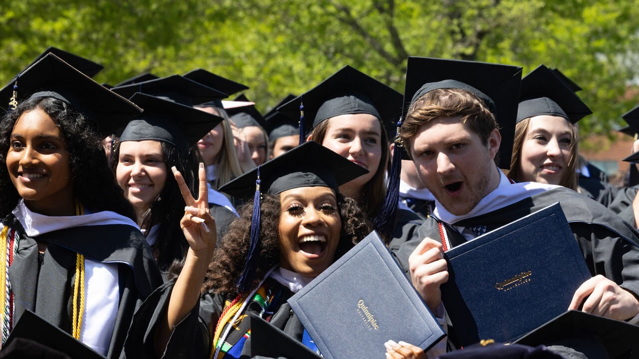 Graduates hold their diplomas and smile happily