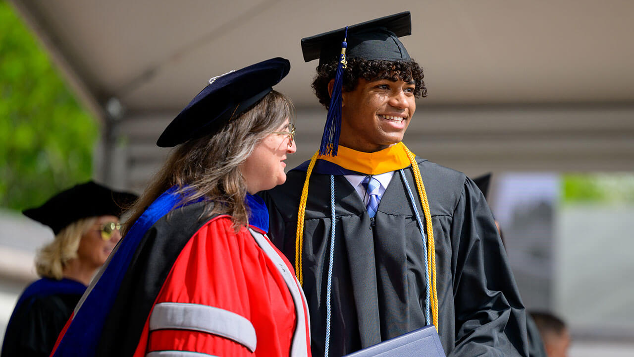 male graduate poses with the dean of health sciences