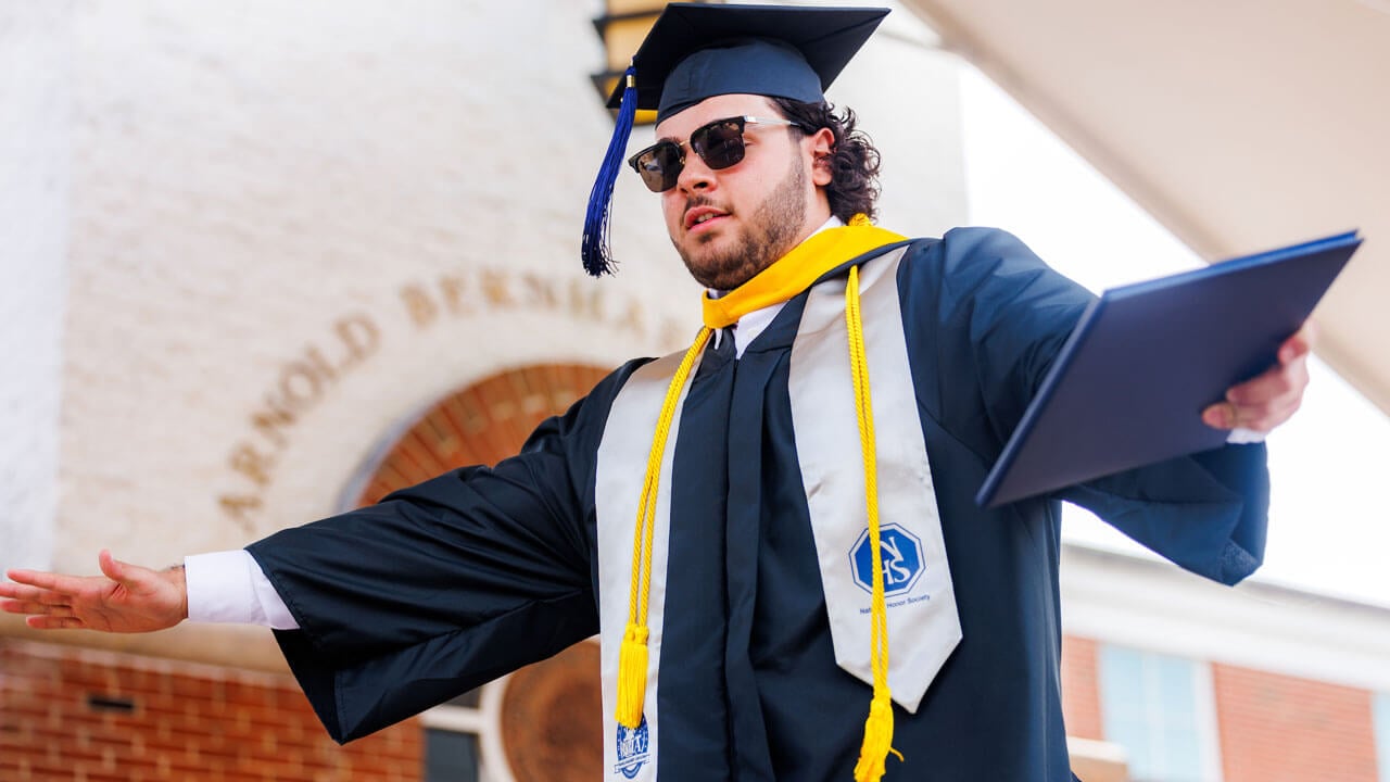 Extends arms during business graduation celebration