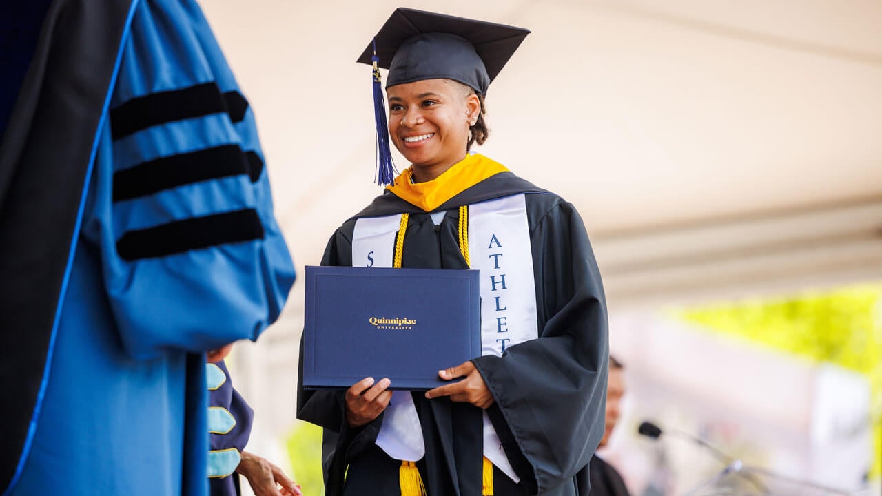 Graduate holding diploma while walking on stage