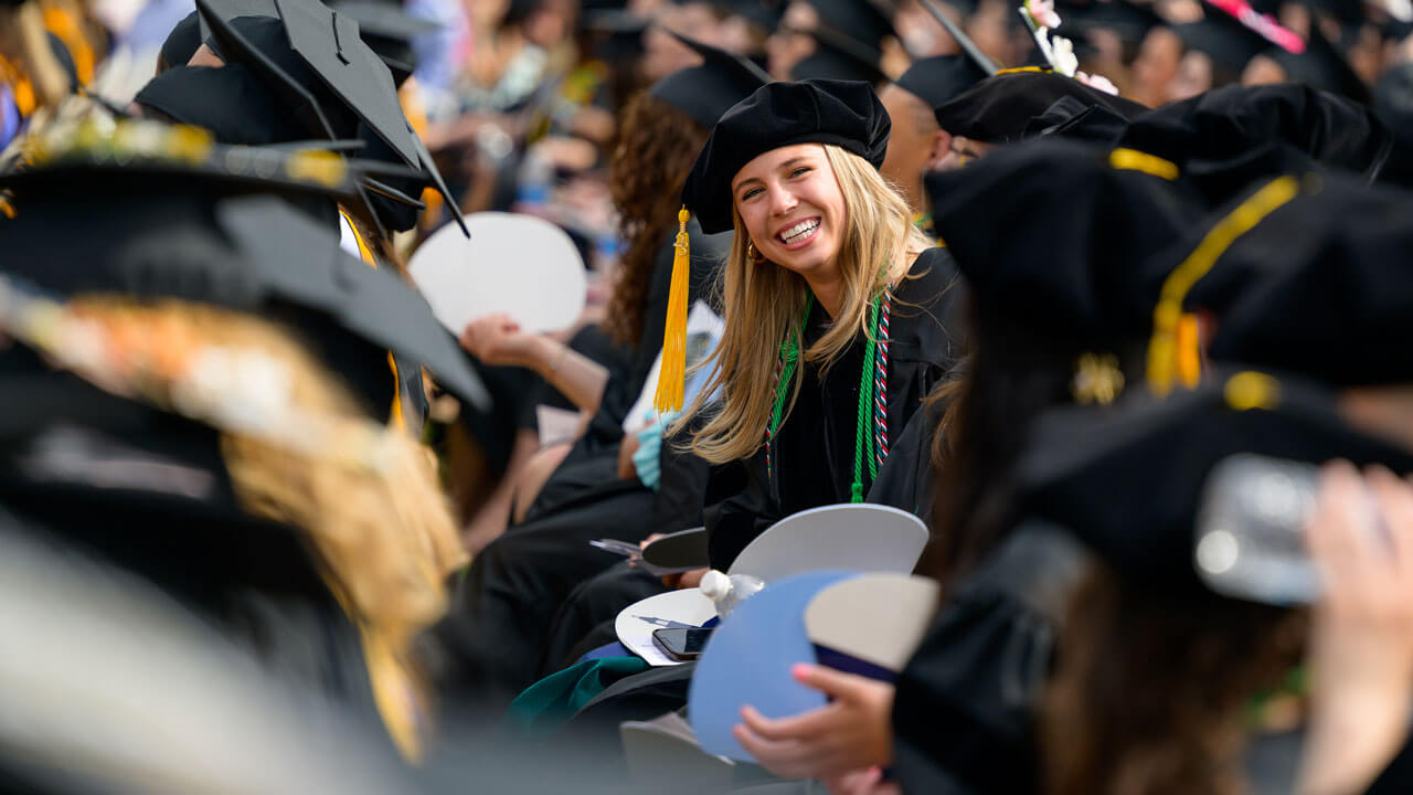 Graduate smiling and laughing as she sits for commencement