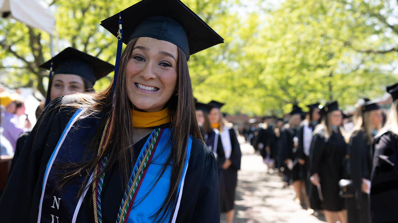 Graduate leaning and smiling in line before commencement