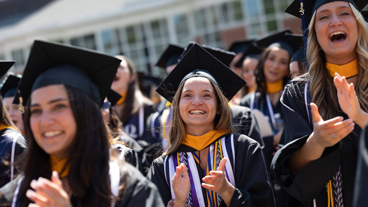 Dozens of graduates clap and cheer enthusiastically