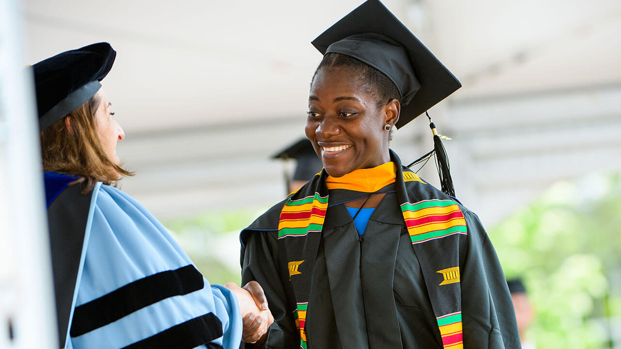 Graduate student shakes the hand of a faculty member