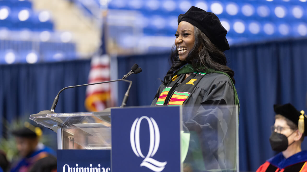 Linda Kerandi laughs as she speaks from a podium onstage