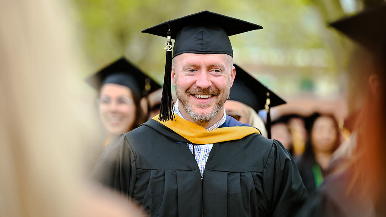 Graduate smiles in line prior to Commencement