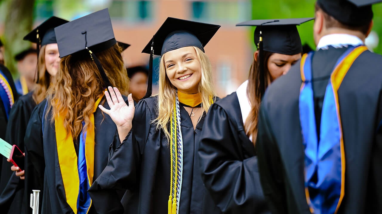 Graduate waves at the camera