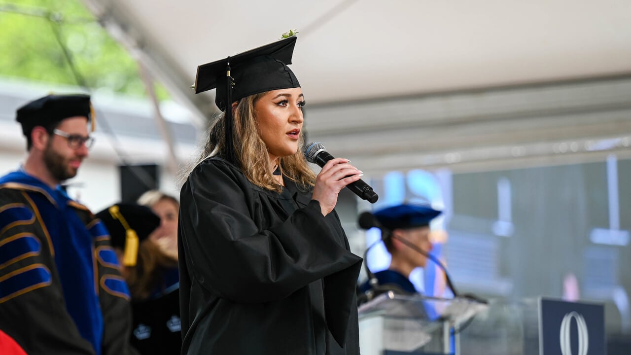 Taina Echevarria sings the national anthem with a microphone on stage