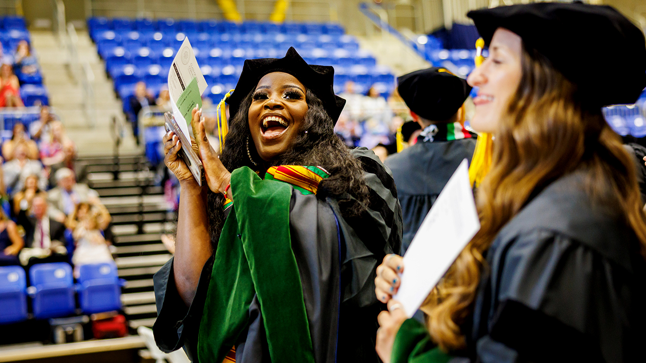 A graduate claps and cheers up to the crowd