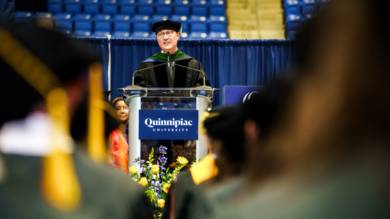 Dean Boiselle speaks from a podium in front of medical school graduates