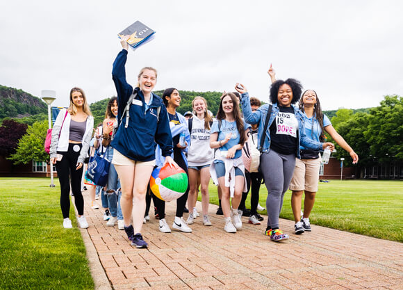 Two Orientation leaders lead a group of new students down a path on the quad