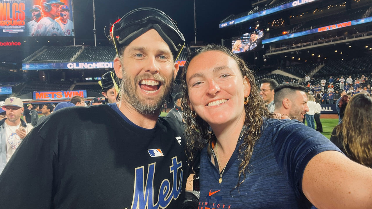 Two individuals take a selfie on a baseball field.