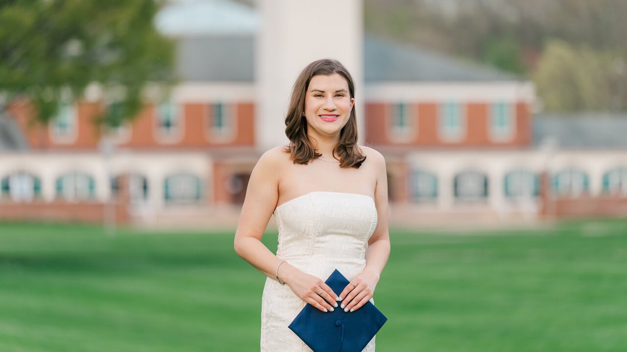 Graduate smiles for a photo on the Mount Carmel Campus quad.
