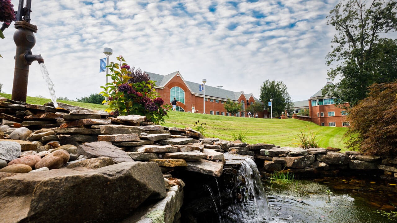 Water flowing down layers of rocks with the School of Communications and Engineering in the background